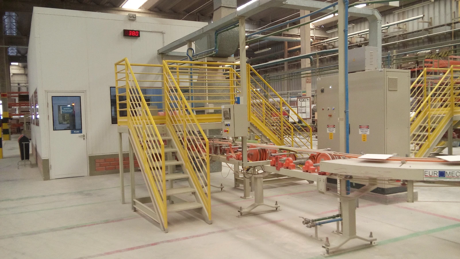 Linha cerâmica com transportadores de rolos, painéis e infraestrutura elétrica instalada junto aos equipamentos.